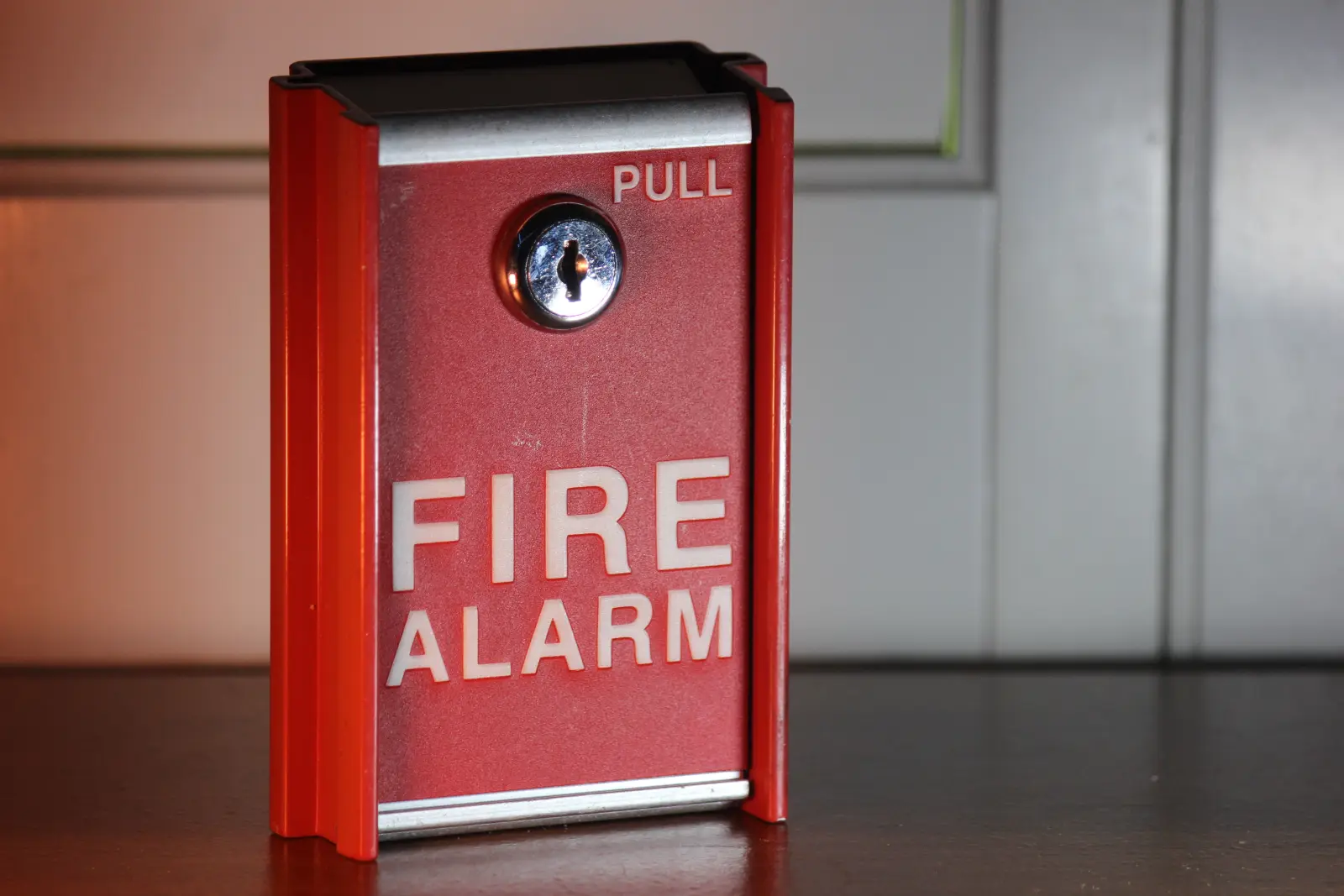Red fire alarm pull station with a key lock, the kind of device a monitored commercial fire alarm reports from