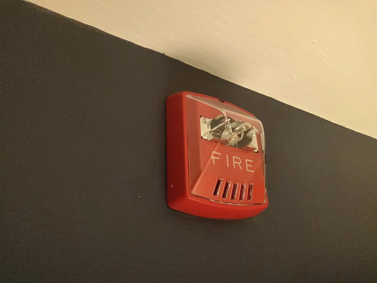 Red wall-mounted fire alarm horn strobe marked FIRE, one of the notification devices that is tested after a panel change